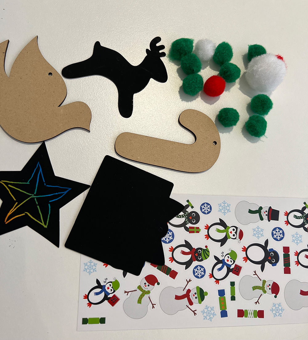 Plain ornaments in the shape of a dove and a cane with stickers of snow sculptures beside them.